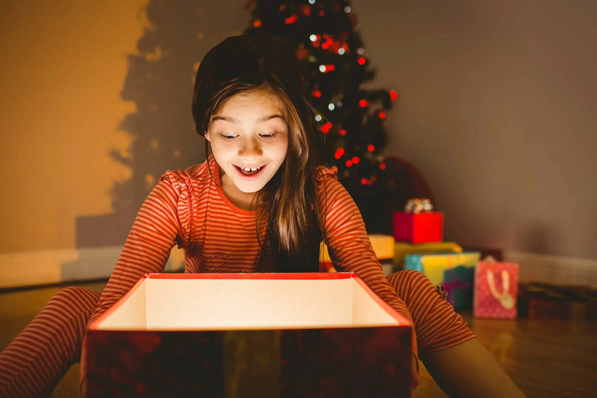 Happy child holding a simple wrapped gift, capturing the joy of a stress-free holiday season.